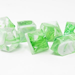 Puede incluir: Conjunto de seis dados verdes y blancos con patrones de remolino. Los dados están hechos de acrílico transparente y tienen una apariencia translúcida.