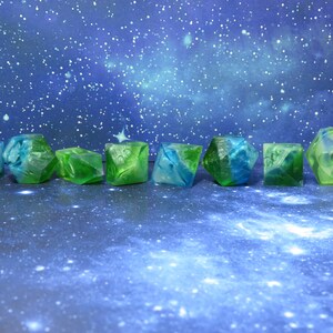 May include: Eight green and blue dice with swirling patterns, resembling a galaxy, on a blue background.