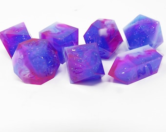 May include: Set of six iridescent dice with a galaxy swirl design in shades of pink, blue, and white. The dice are made of resin and have a glittery finish.