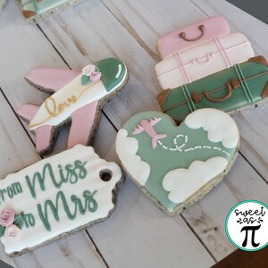 May include: A set of six decorated cookies featuring a heart-shaped cookie with a plane flying over clouds, a tag cookie with the text "from Miss to Mrs", a plane cookie with the text "love", and three stacked luggage cookies. The cookies are decorated with green, pink, and white icing.