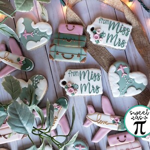 May include: Assortment of decorated sugar cookies with travel themes. Cookies feature airplanes, luggage, hearts, and tags with the text "From Miss to Mrs".