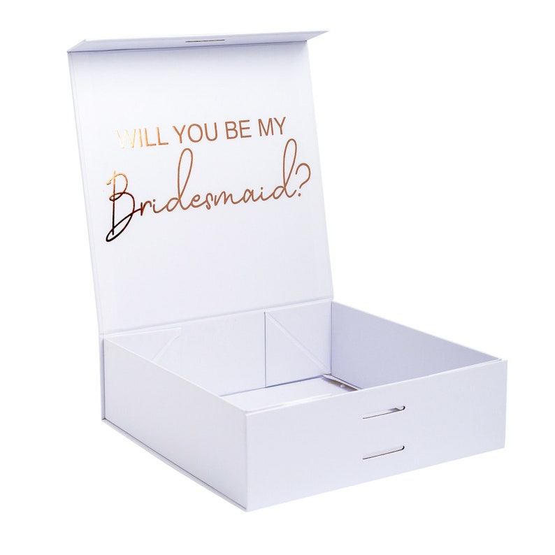 May include: White gift box with a gold foil inscription that reads "Will you be my Bridesmaid?"