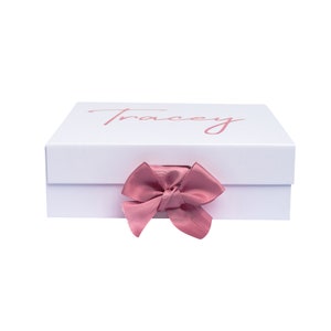 May include: White gift box with a pink ribbon and the name "Tracey" printed on the top.
