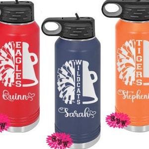 May include: Three personalized stainless steel water bottles with different team names and cheerleading pom-poms. The bottles are red, blue, and orange with white lettering. The names on the bottles are Quinn, Sarah, and Stephenia.