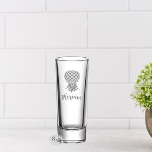 May include: A clear glass shot glass with a pineapple design and the name "Miriam" etched on the side.