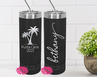 May include: Black insulated tumbler with a silver lid and straw. One side features a palm tree graphic with "Punta Cana 2023". The other side has the name "bethany" in cursive. The tumbler is designed to keep drinks cold.