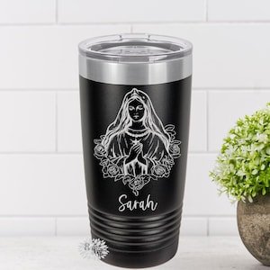 Puede incluir: Un vaso de acero inoxidable negro con un dise&ntilde;o blanco de la Virgen Mar&iacute;a con rosas y el nombre "Sarah" en la parte inferior.