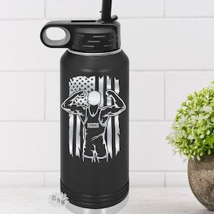 May include: Black insulated water bottle with a black lid and straw. The bottle features a white graphic of a weightlifter in front of a distressed American flag design. The name "MASON" is printed below the weightlifter.