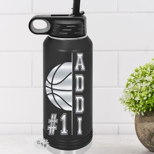 May include: Black stainless steel water bottle with a white basketball graphic and the name "ADDI #1" printed on the side.