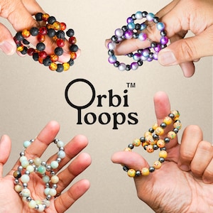 May include: Four Orbi Loops bracelets in various colors are displayed. One bracelet features black and red lava beads, another has purple and silver beads, a third has light green and silver beads, and the last has yellow and red beads. The Orbi Loops logo is in the center.
