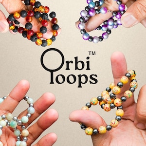May include: Four beaded bracelets in various colors are held up by hands. The bracelets include black, red, orange, yellow, and gray beads. The text "Orbi loops" is in the center of the image.