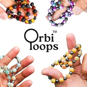 May include: Four circular beaded bracelets labeled Orbi Loops. One features black lava and amber-colored beads, another has iridescent purple and blue beads, one contains pale green and silver beads, and the last has yellow speckled beads with silver accents.