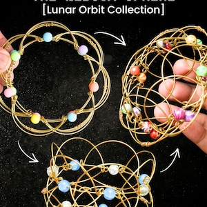May include: Three gold wire sphere sculptures with colourful beads. The text "THE NEBOVA SPHERE [Lunar Orbit Collection]" is at the top. Each sphere has a unique design and bead arrangement, showcasing a handcrafted aesthetic.