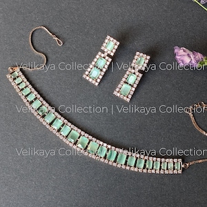 May include: A delicate gold necklace with a row of light green rectangular stones and clear rhinestones. Matching earrings with light green stones and rhinestones.