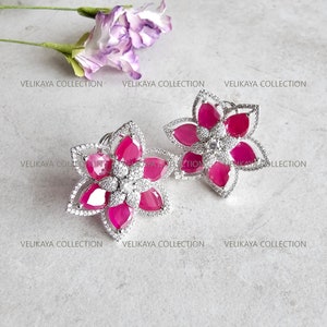 Può includere: Un paio di orecchini d'argento a forma di fiore con pietre preziose rosa e pietre di zircone cubico trasparenti.