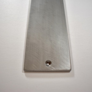 May include: A brushed silver metal door handle with a single hole for mounting.