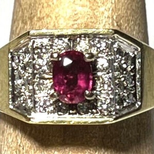 Peut inclure: Une bague en or avec un gros rubis ovale entouré de diamants plus petits.