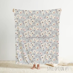 May include: A soft, gray and white baby blanket with a floral pattern of pink and white flowers. The blanket has the name "grace smith" written in cursive on it.  Style option #3.