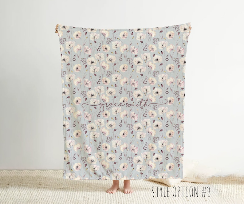 May include: A soft, gray and white baby blanket with a floral pattern of pink and white flowers. The blanket has the name "grace smith" written in cursive on it.  Style option #3.