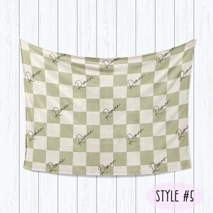 Puede incluir: Una manta de franela a cuadros verdes y blancos con el nombre "Roman" repetido en todo el dise&ntilde;o. La manta est&aacute; colgada en una pared de madera blanca. El texto "STYLE #5" est&aacute; escrito debajo de la manta.