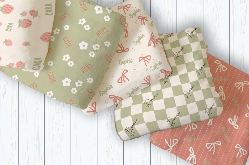 Puede incluir: Cinco mantas para beb&eacute; con diferentes patrones y nombres. Las mantas est&aacute;n hechas de tela suave y afelpada y presentan una variedad de colores, incluyendo verde, crema y rosa. Los nombres en las mantas son Cara, Vicky, Sophie y Roman.