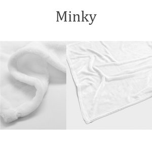 May include: Close-up of a white minky fabric. The fabric is soft and plush, with a subtle texture. The fabric is shown in two different positions, one folded and one unfolded.
