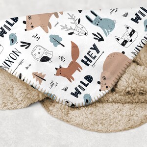 May include: White fleece blanket with a woodland animal print. The blanket features a fox, deer, owl, bear, rabbit, raccoon, and birds. The text "Wild Hey Nixon" is printed on the blanket.