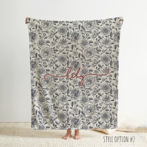 May include: A white throw blanket with a black floral pattern and the name "lily" written in red cursive script.