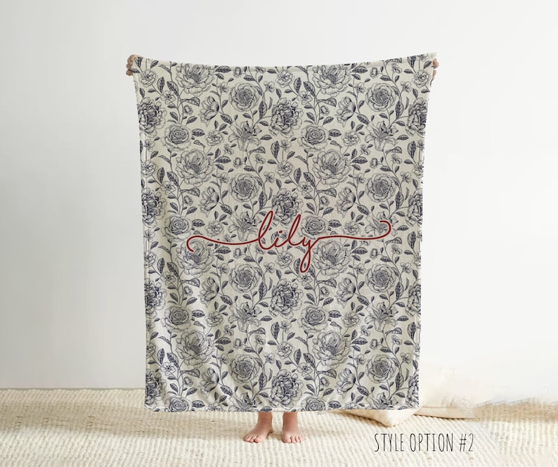 May include: A white throw blanket with a black floral pattern and the name "lily" written in red cursive script.