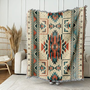 Op de afbeelding: Een geweven deken met een geometrisch patroon in tinten blauw, rood en beige. De deken heeft een franje rand.