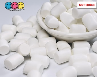 May include: A white bowl filled with white, round, foam marshmallows. The bowl is on a white surface with more marshmallows scattered around it. The text "NOT EDIBLE" is printed in black on a white rectangle.