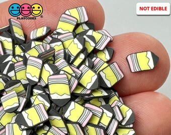 May include: A large pile of yellow, black, and pink pencil-shaped resin embellishments. The embellishments are small and perfect for adding a touch of whimsy to crafts.