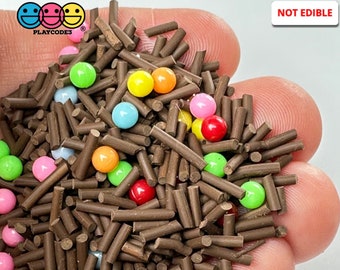 May include: A close-up of brown sprinkles with colorful round sprinkles. The text "NOT EDIBLE" is in red letters at the top of the image.