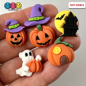 May include: A set of six Halloween-themed polymer clay charms, including a witch's hat, a pumpkin with a face, a ghost holding a pumpkin, a pumpkin with a house, a moon with a bat and a haunted house, and a pumpkin with a window.  NOT EDIBLE.