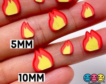 May include: Small, colorful flame-shaped embellishments in red and yellow, with a black outline. The image includes sizes 5mm and 10mm. The text "NOT EDIBLE" is also present. The product is likely for crafts or nail art.