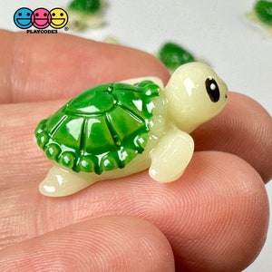 May include: A small, green and cream-colored turtle figurine. The turtle has a detailed green shell and a cream-colored body. The image includes the "PLAYCODE3" logo with three smiley faces.