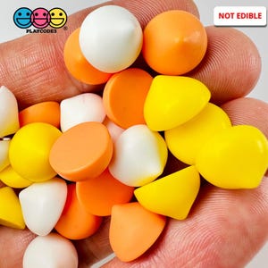 May include: A handful of colorful, non-edible candies in white, orange, and yellow. The candies are various shapes, including round and wedge-shaped. The image includes the text "NOT EDIBLE" and the logo "PLAYCODE3".