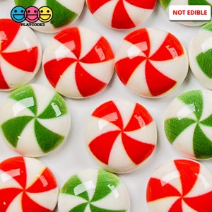May include: Assortment of red and green candy cane swirl patterned round ornaments. The ornaments are not edible.  NOT EDIBLE is printed on the image.