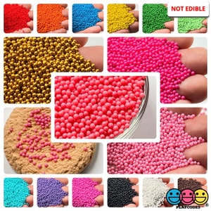 May include: Assortment of colorful, round, non-edible beads in various colors, including gold, pink, red, blue, green, purple, black, white, and brown. The beads are displayed in a grid pattern on a white background. The text "NOT EDIBLE" is displayed in the top right corner of the image.