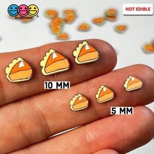 May include: Two sizes of pumpkin pie shaped resin embellishments. The larger size is 10 mm and the smaller size is 5 mm.  The embellishments are orange, yellow, and white.  Not edible.