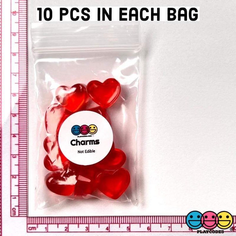 May include: A clear plastic bag filled with ten red heart-shaped charms. The bag has a label that reads "Charms Not Edible".