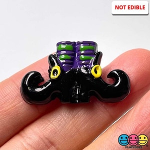 May include: A black witch's hat with a purple and green striped top and yellow eyes. The hat is made of plastic and is a Halloween decoration.