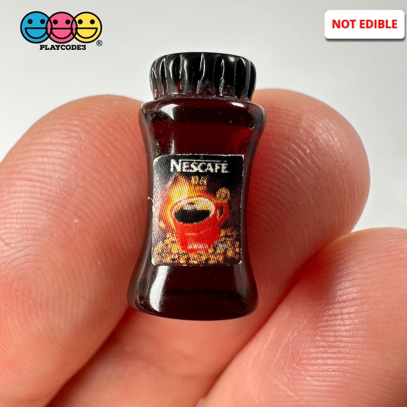May include: Miniature brown plastic Nescafe coffee bottle with a black cap. The label features a red coffee cup graphic and the text "NESCAFE". The bottle is labeled "NOT EDIBLE".