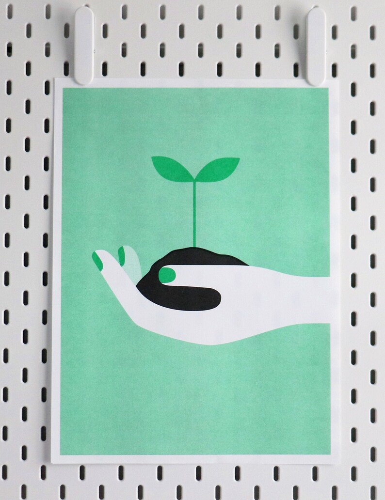Op de afbeelding: Een witte hand met groene nagels houdt een kleine zwarte pot vast met een groene scheut die eruit groeit. De achtergrond is lichtgroen.