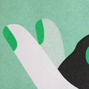Op de afbeelding: Een close-up van een groene en witte stof met een zwart en groen ontwerp. Het ontwerp toont een hand met een omhoog wijzende vinger en een gebogen vorm.