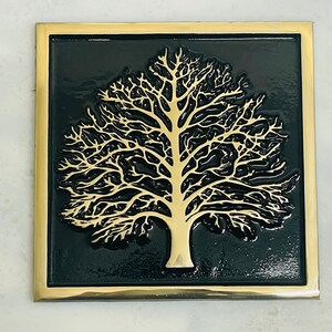May include: A gold-colored tree silhouette on a black background, framed with a gold border.