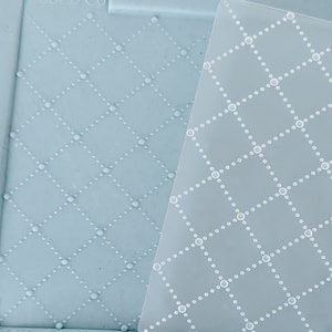 May include: A clear plastic embossing template with a repeating diamond pattern of small circles. The template is lying on top of a blue silicone mat with the same pattern embossed into it. The mat has the text "Babe & Co" printed on it.