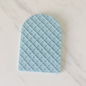 May include: A light blue silicone cake decorating tool with a repeating pattern of overlapping circles.