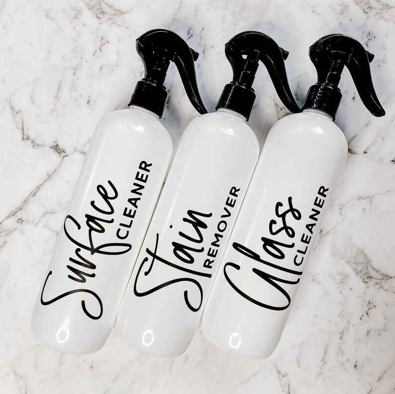 May include: Three white spray bottles with black trigger tops and labels. The labels read "Surface Cleaner", "Stain Remover", and "Glass Cleaner".