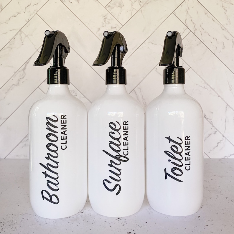 May include: Three white spray bottles with black trigger tops and black labels. The labels read "Bathroom Cleaner", "Surface Cleaner", and "Toilet Cleaner".